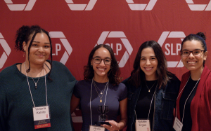 Four woman smiling in front of a red backdrop.